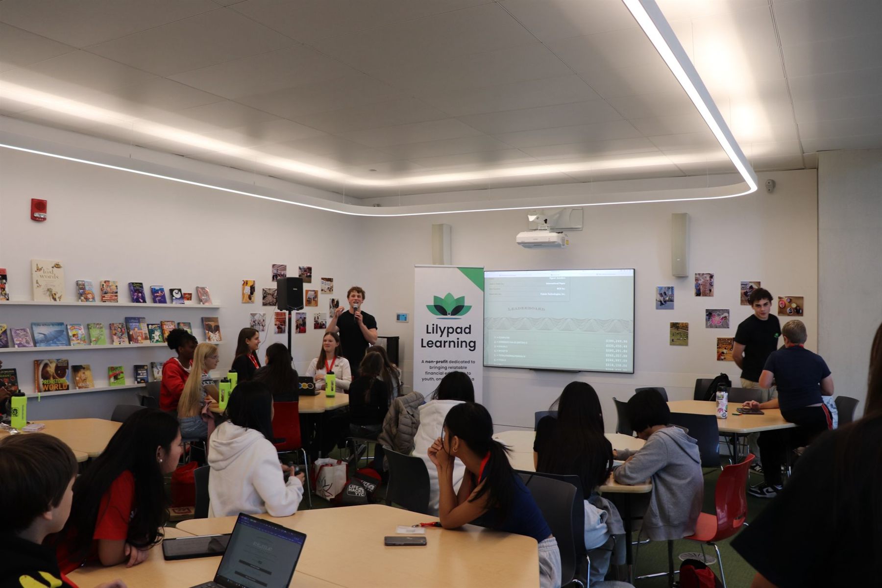 A Lilypad educator on the mic revealing the Build Your Stax leaderboard to a room of students