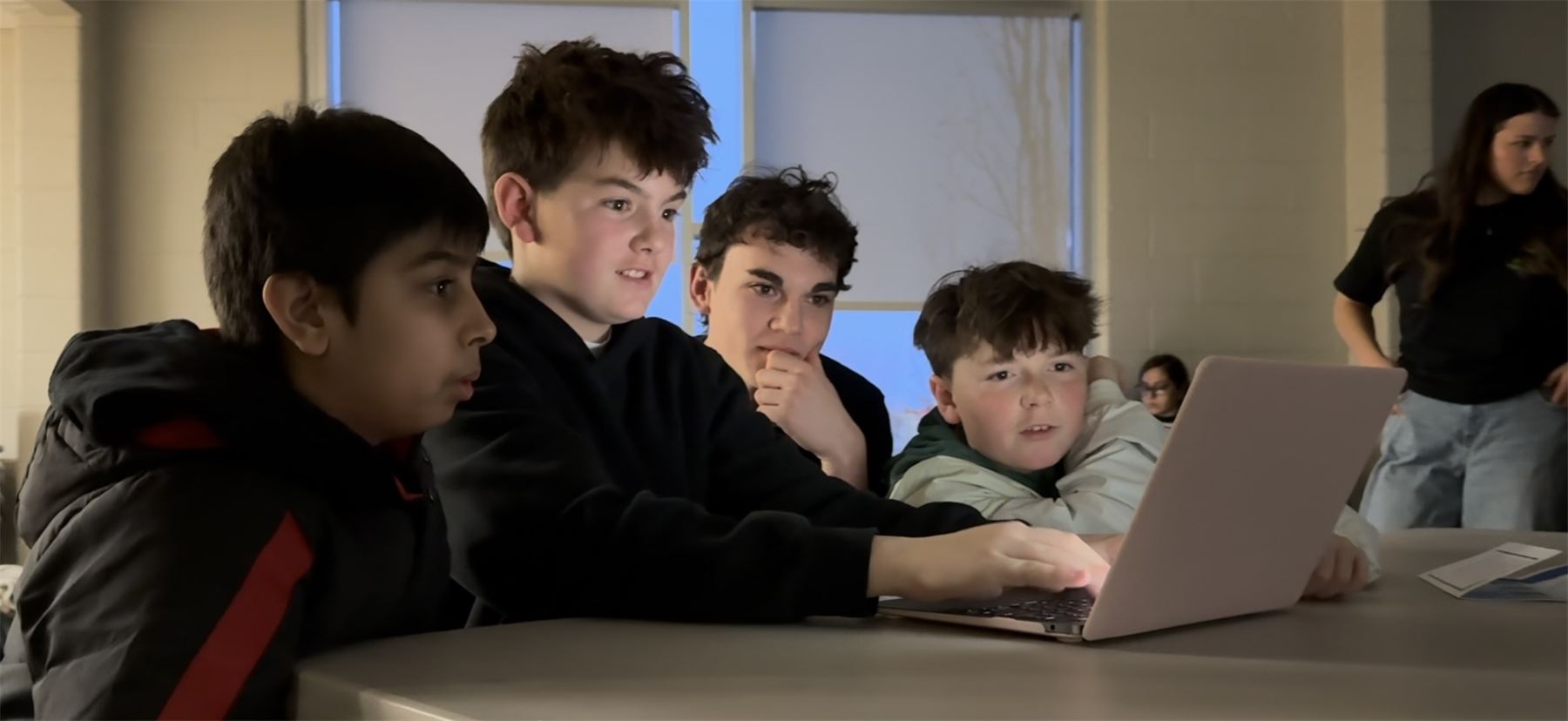 Four youth gathered around a laptop during a Lilypad Learning activity